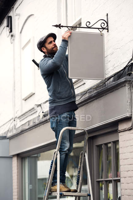 Man fixing a painted name sign — Stock Photo