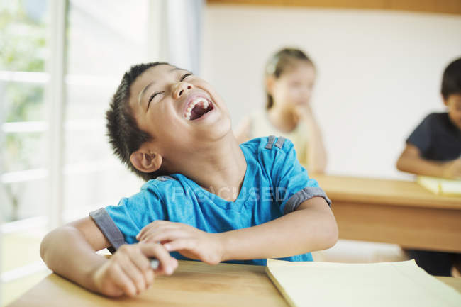 Garçon assis dans une classe et riant . — Photo de stock