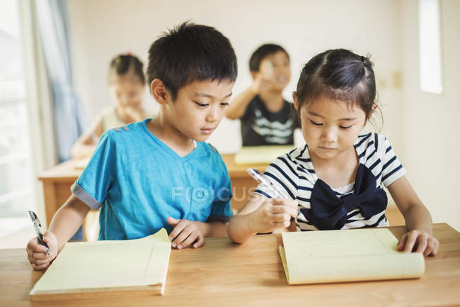 Niños trabajando juntos en un aula - foto de stock
