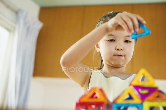 Chica construyendo una estructura con formas geométricas . - foto de stock
