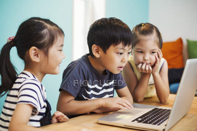 Trois enfants utilisant un ordinateur portable — Photo de stock