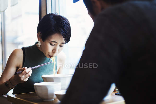 Man and woman eating noodles — Stock Photo