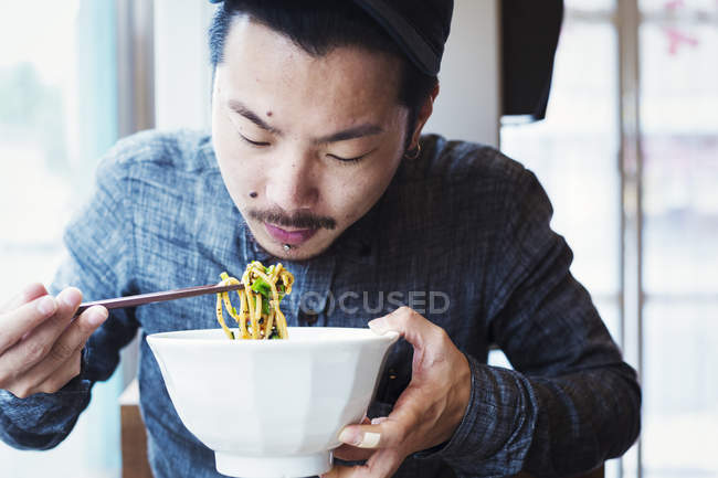 Человек ест раменную лапшу — стоковое фото