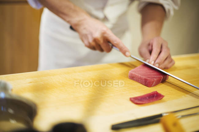 Chef rebanando pescado para hacer sushi - foto de stock