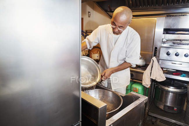 Chef trabajando en una pequeña cocina comercial - foto de stock