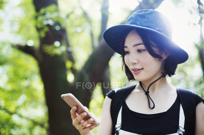 Жінка використовує мобільний телефон у лісі — стокове фото