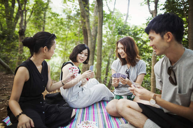 Women and a man playing cards in a forest — Stock Photo