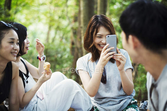 Women and a man sitting in a forest. — Stock Photo