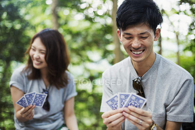 Woman and a man playing cards in a forest. — Stock Photo