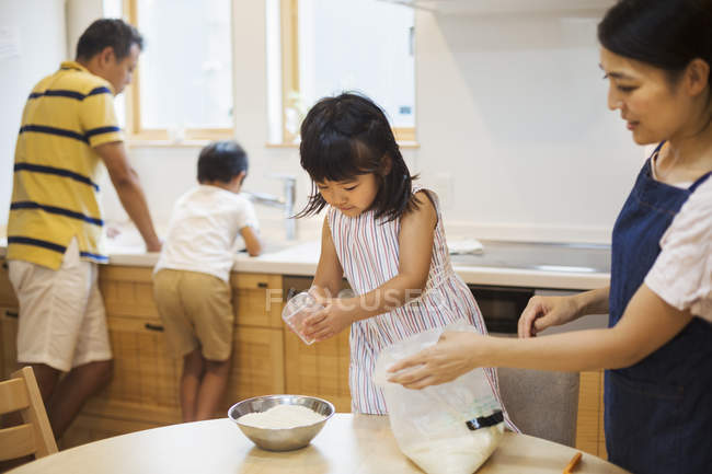 Eltern und zwei Kinder bereiten eine Mahlzeit zu. — Stockfoto