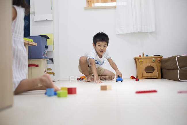 Мальчик играет с машинами на полу . — стоковое фото