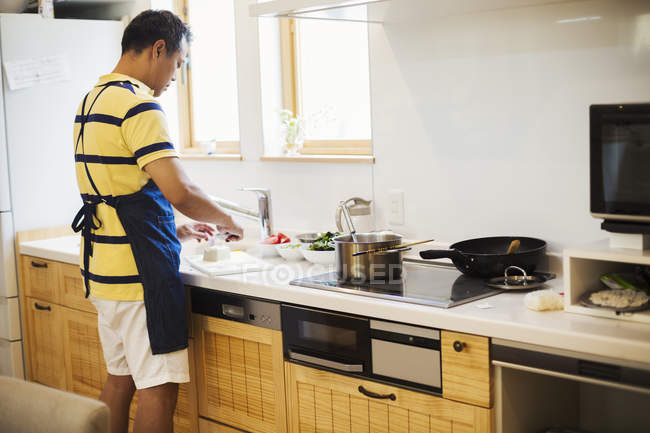 Homem de avental azul preparando uma refeição — Fotografia de Stock