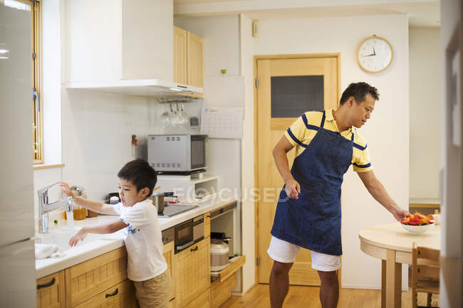 Man preparing a meal with his son. — Stock Photo
