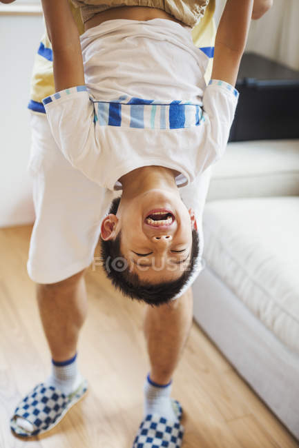 Man holding his son upside down — Stock Photo