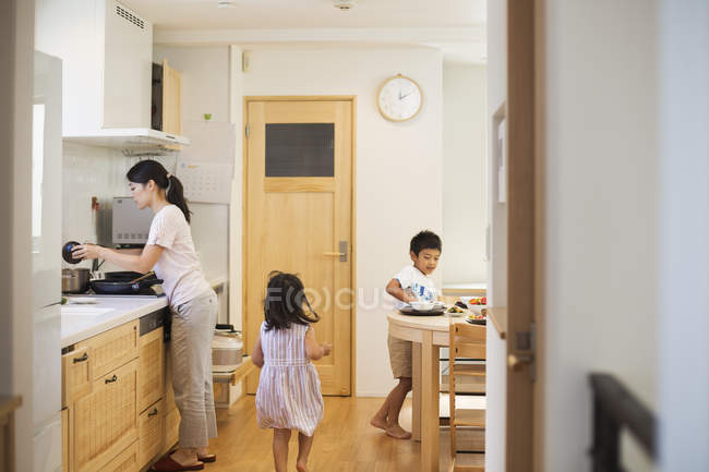 Femme et deux enfants dans la cuisine — Photo de stock