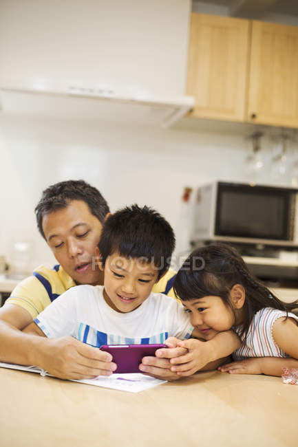 Hombre y niños con teléfono inteligente - foto de stock