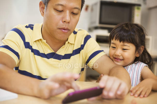 Homem usando um telefone inteligente com a filha — Fotografia de Stock