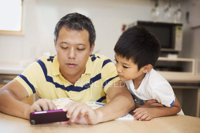 Mann und Sohn schauen aufs Smartphone. — Stockfoto
