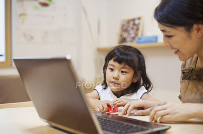 Женщина и ее дочь с ноутбуком — стоковое фото