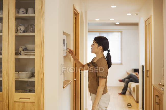 Frau stellt Thermostat an Wand ein — Stockfoto