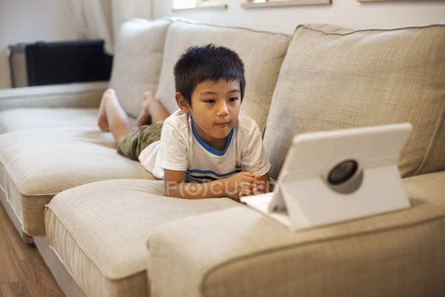 Junge schaut auf ein digitales Tablet. — Stockfoto