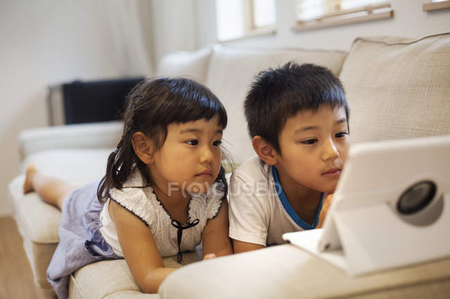 Ragazzo e ragazza guardando un tablet digitale . — Foto stock