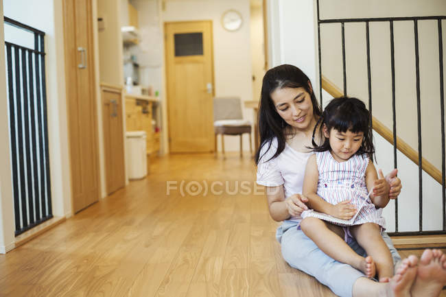 Woman with daughter looking at a book. — Stock Photo
