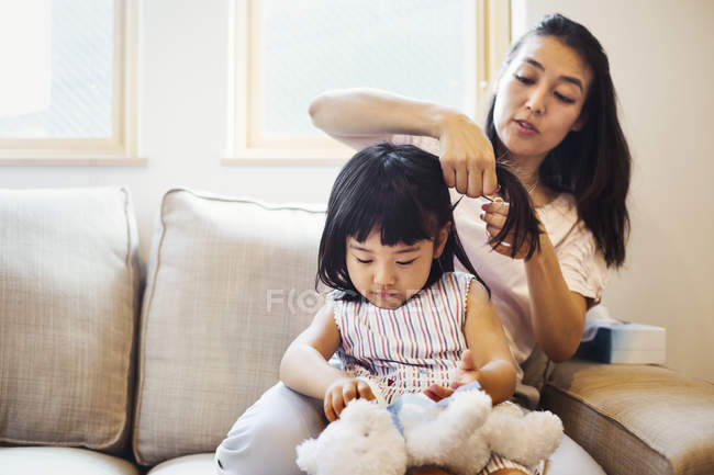 Madre peinando el cabello de su hija . - foto de stock