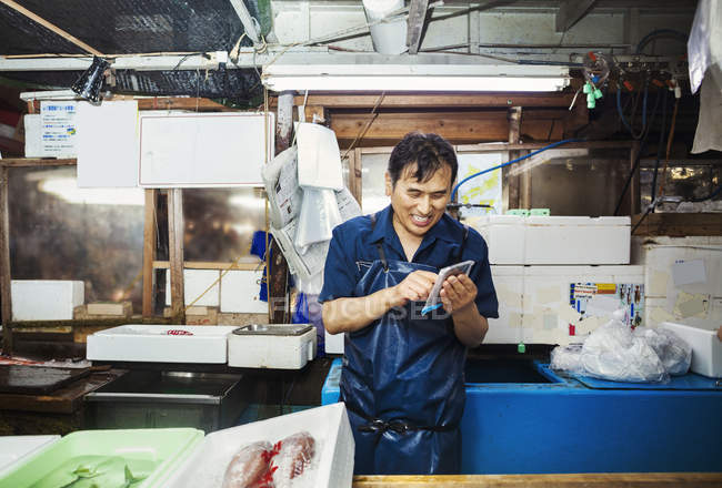 Hombre que trabaja en el mercado tradicional del pescado - foto de stock