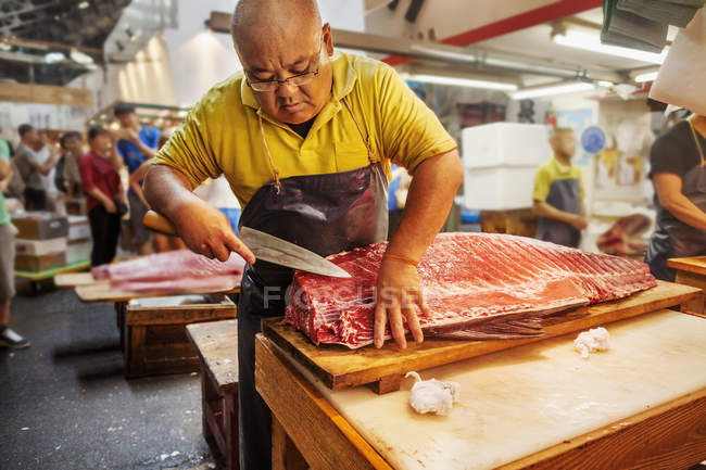 Pescadero que trabaja en el mercado tradicional de pescado - foto de stock
