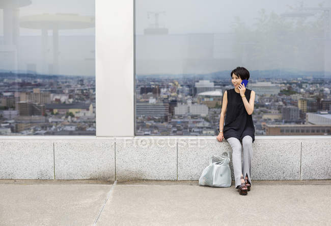 Жінка біля вікна з видом на місто — стокове фото