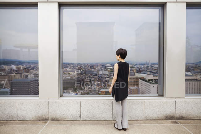 Mujer de pie mirando sobre una ciudad - foto de stock