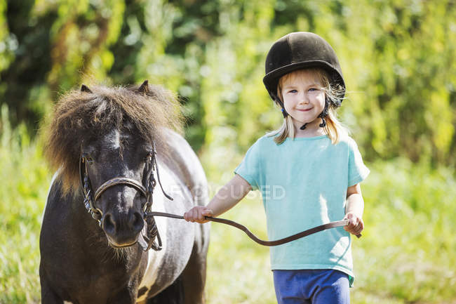 Chica y un pony en un campo . - foto de stock