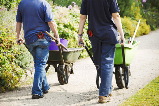 Gardeners pushing wheelbarrows — Stock Photo