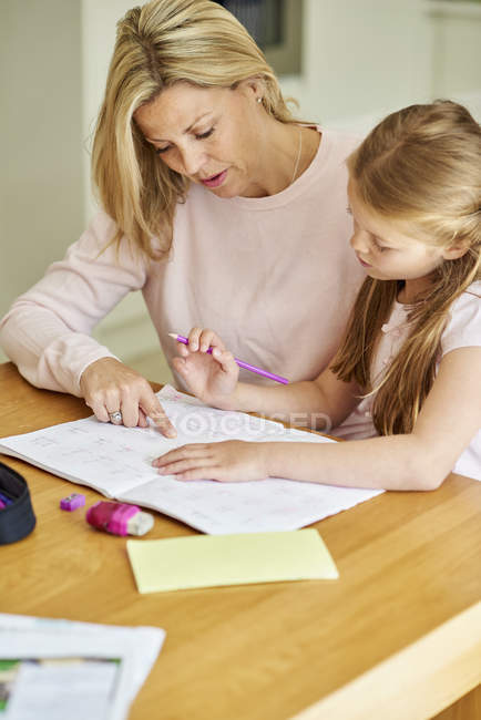Woman and her daughter seated at a table — Stock Photo