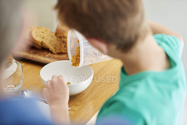 Junge gießt Müsli in Schüssel. — Stockfoto