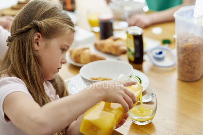 Mädchen gießt Orangensaft ein — Stockfoto