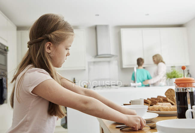 Girl laying the table for breakfast. — Stock Photo