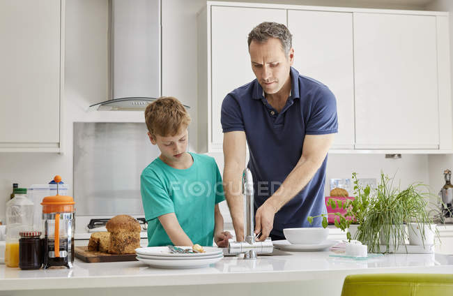 Hombre y niño limpiando las placas - foto de stock