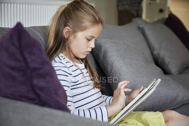 Chica sentada mirando una mesa digital - foto de stock