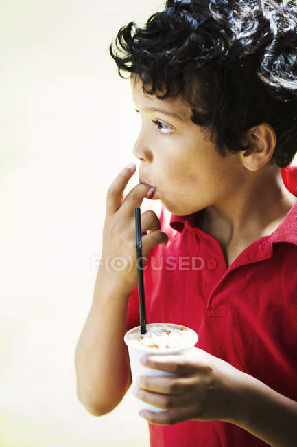 Мальчик держит пластиковую чашку — стоковое фото