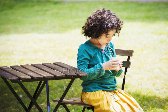 Girl sitting outdoors at a table — Stock Photo