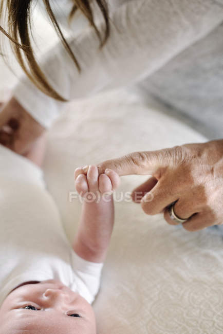 Bebé agarre dedo madre - foto de stock
