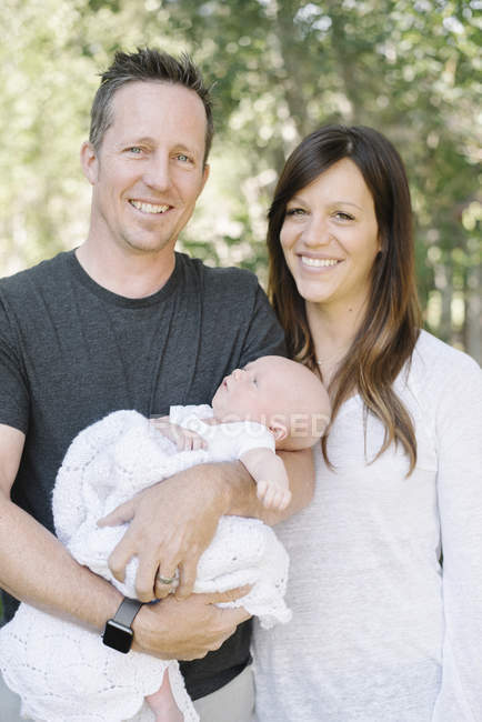 Feliz pareja sosteniendo bebé - foto de stock