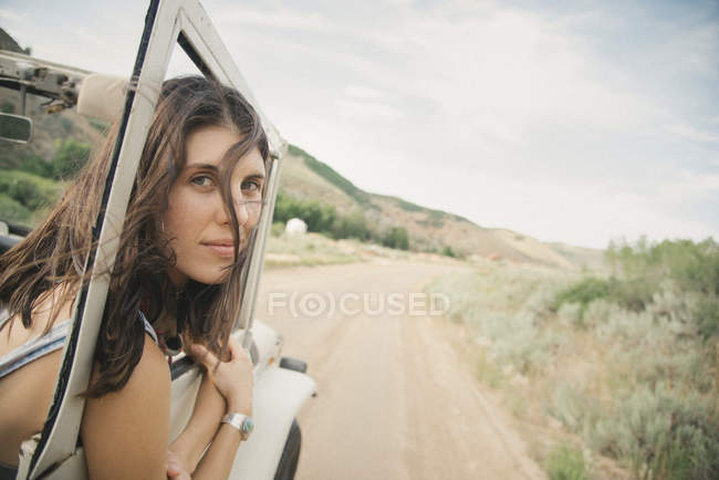 Woman leaning out of moving jeep — Stock Photo