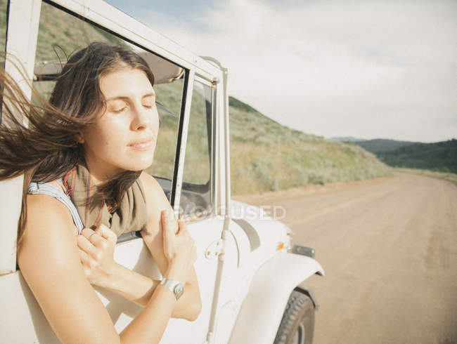 Woman leaning out of moving jeep — Stock Photo