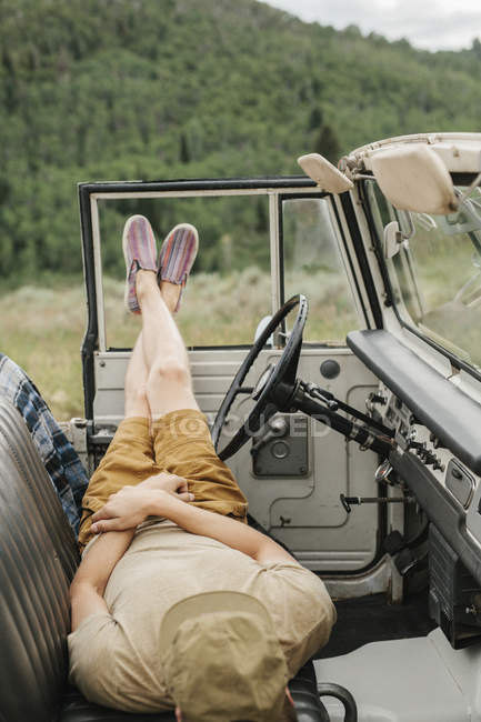 Homme couché sur les sièges avant voiture — Photo de stock