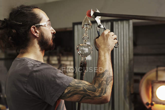 Soplador de vidrio trabajando en pieza de vidrio - foto de stock
