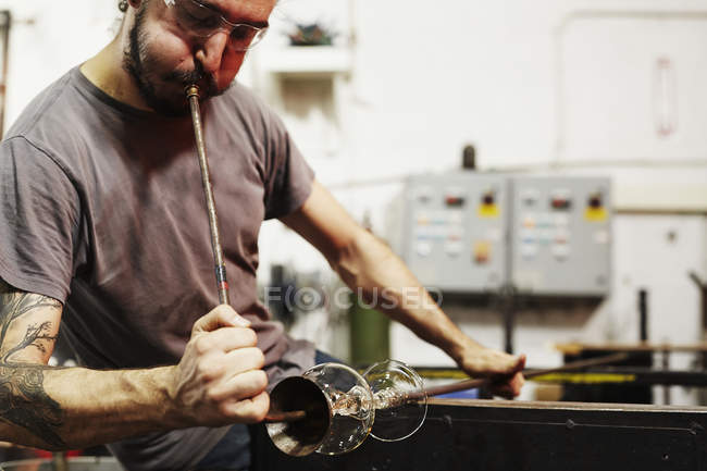 Soplador de vidrio trabajando en pieza de vidrio - foto de stock