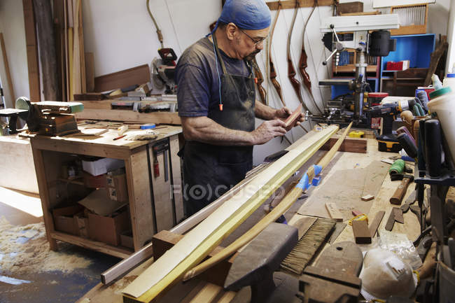 Man working on wooden bow — Stock Photo